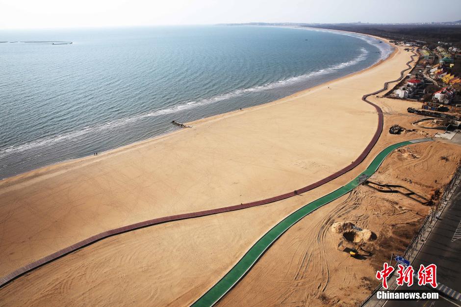 3月13日，秦皇島萬米臨海沙灘木棧道。據(jù)了解，該木棧道全長(zhǎng)約4200米，與北戴河區(qū)原有的7500米木棧道對(duì)接后全線總長(zhǎng)度1.17萬米，整個(gè)木棧道東起秦皇島體育基地游船碼頭，西至北戴河濕地公園，呈波浪形蜿蜒10.4公里海岸線。 中新社發(fā) 曹建雄 攝 CNSPHOTO